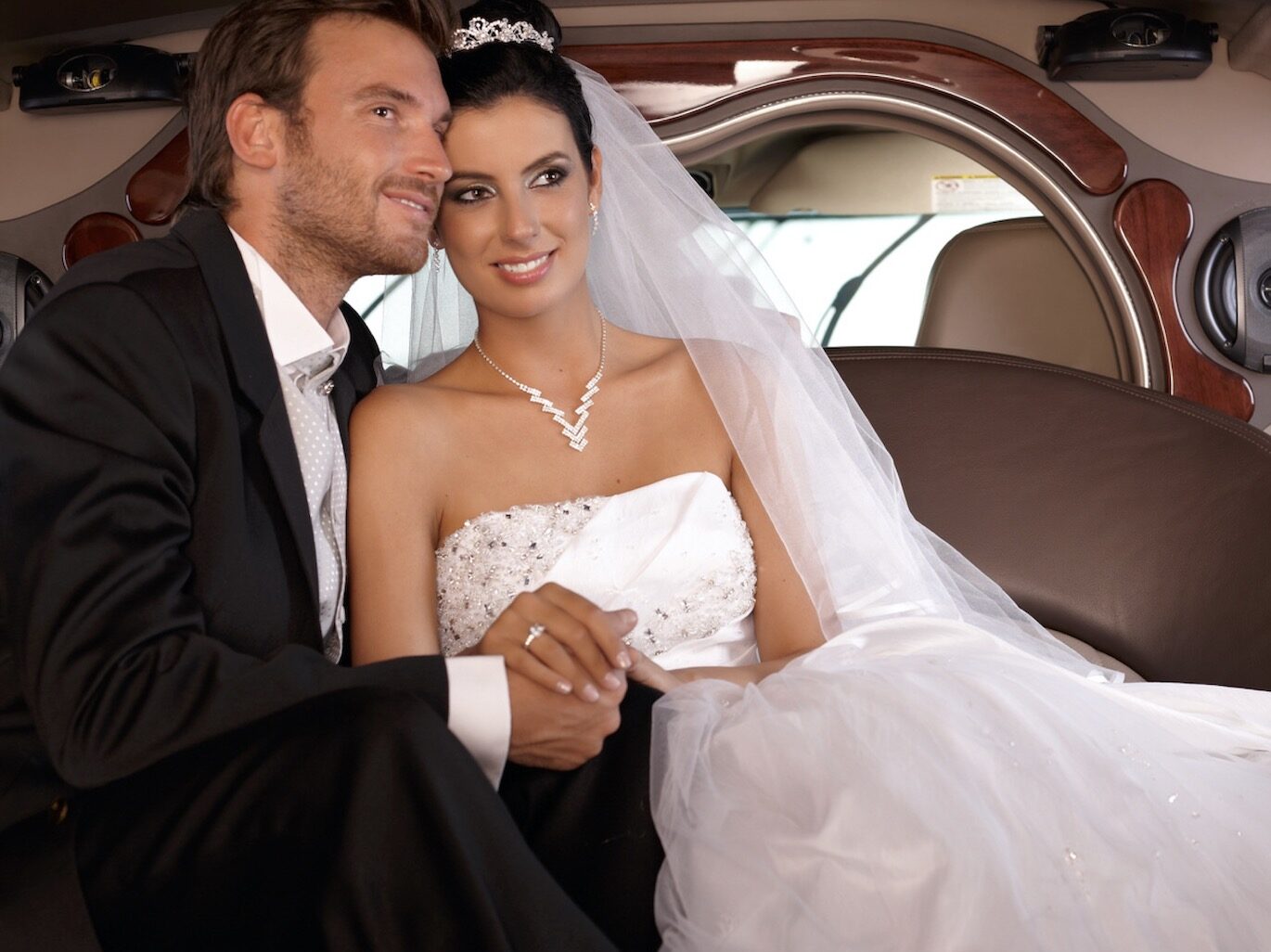 Bride and groom in limo smiling happily