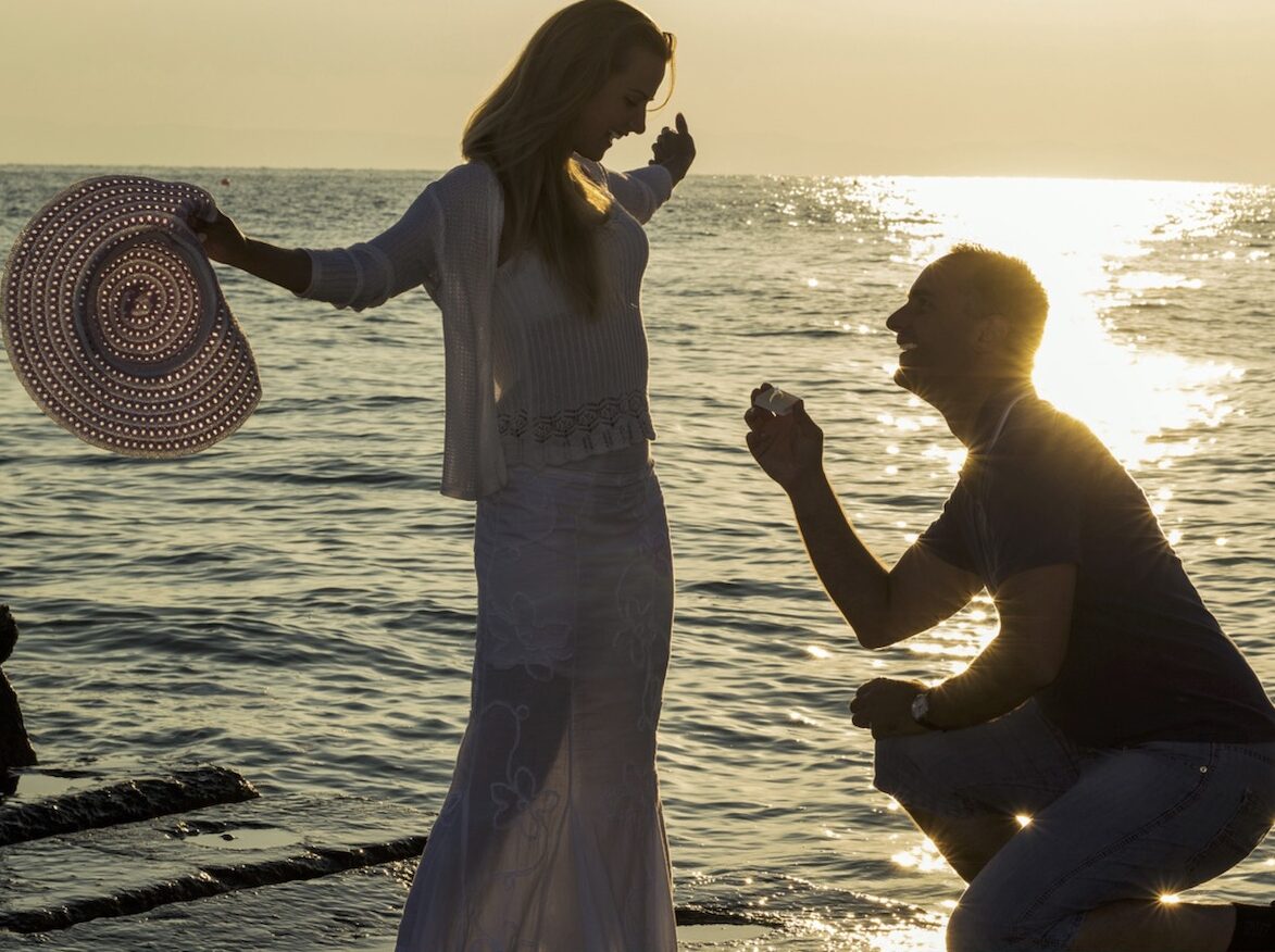 Sunset marriage proposal next to ocean on beach