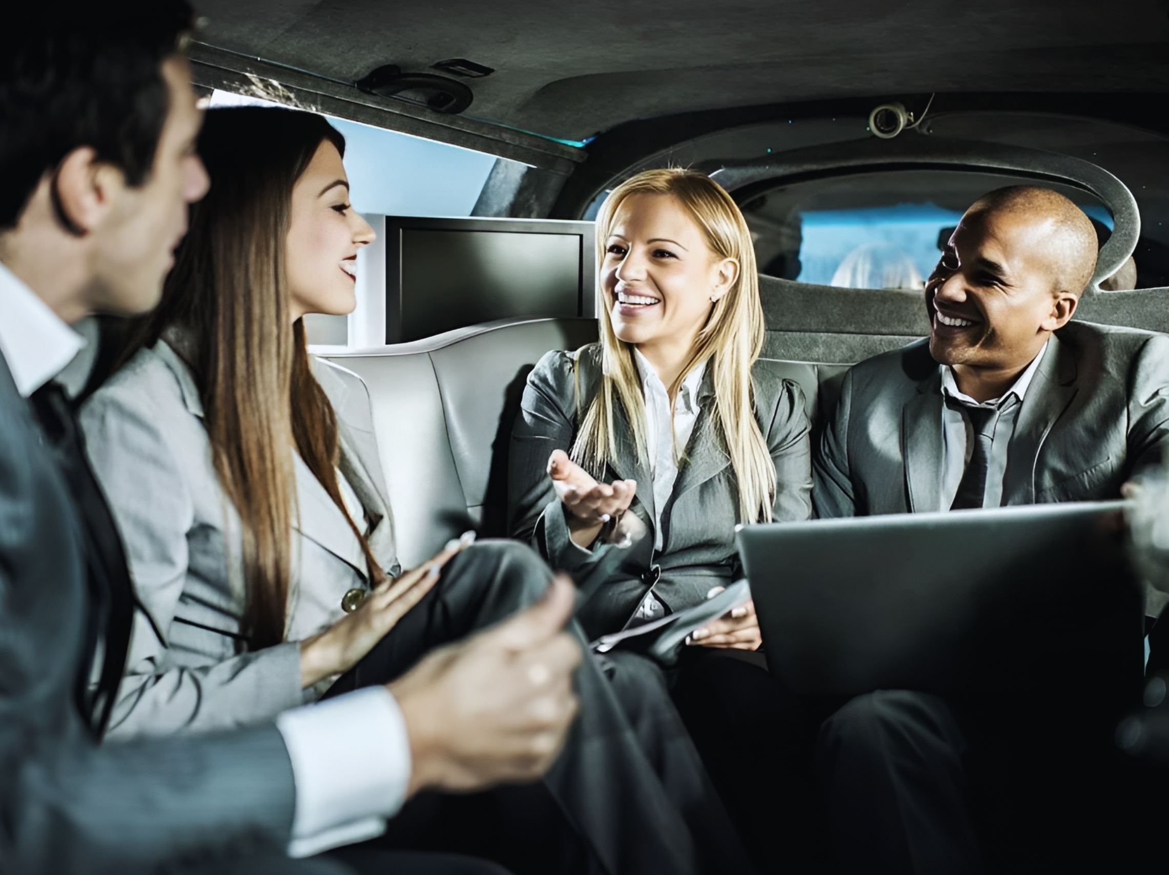 Featured_Four business professionals sitting together in a limousine, smiling and engaged in a lively conversation.